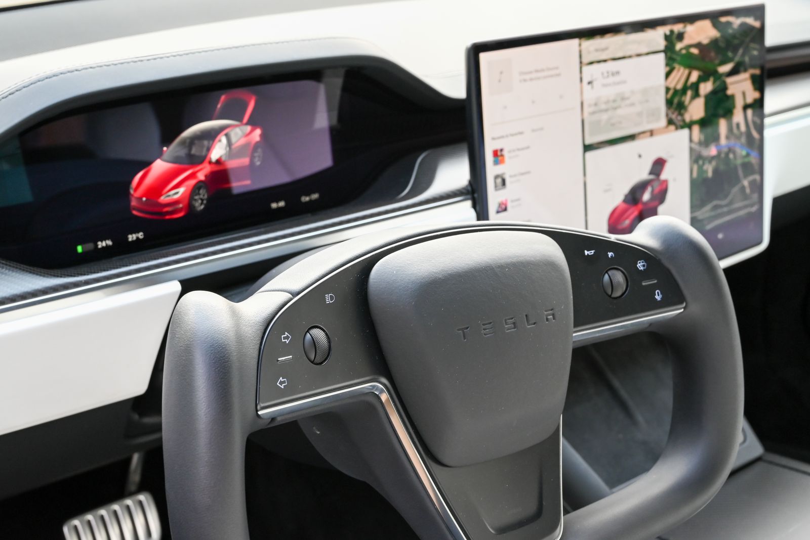 Real Tesla interior with a steering yoke, central touchscreen and digital dashboard